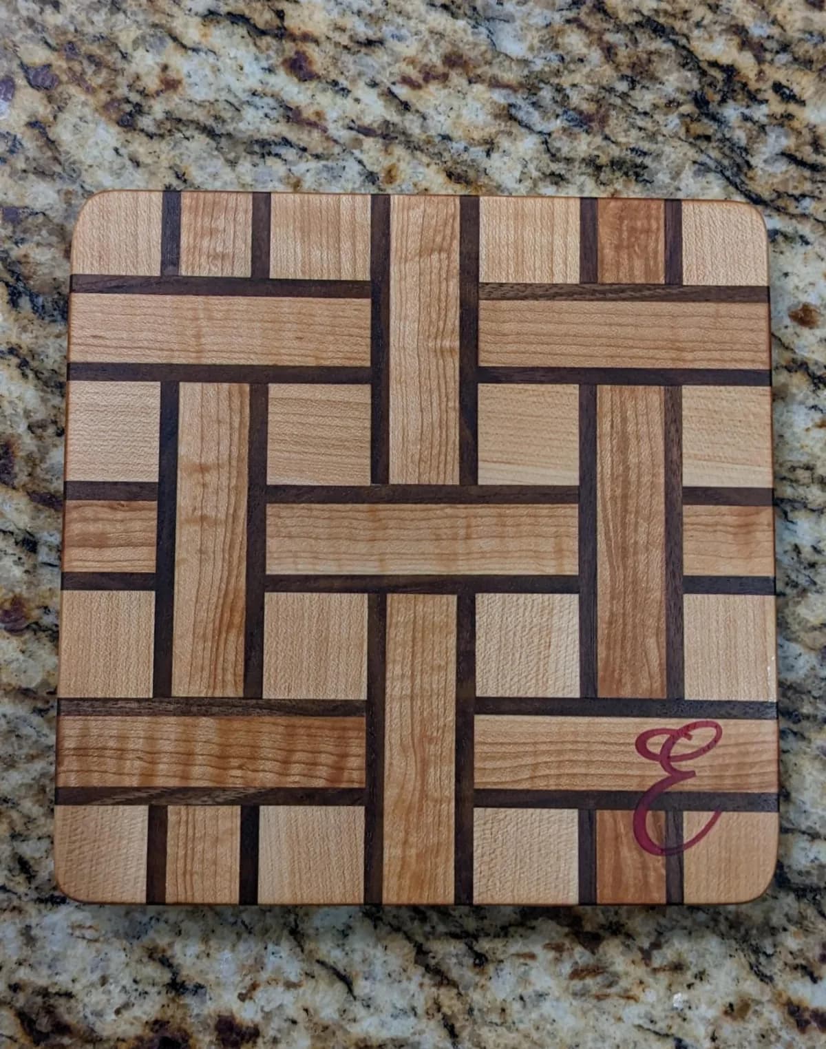 Handcrafted multi wood species square cutting board made in weave pattern with epoxied monogram letter.